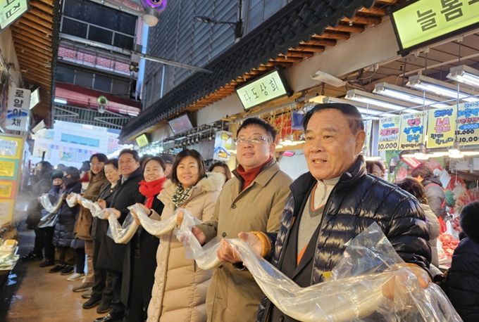 김현수 수원시 제1부시장(오른쪽 2번째), 이재식 수원시의회 의장 등이 시민들과 함께 가래떡 나눔 행사에 참여하고 있다.