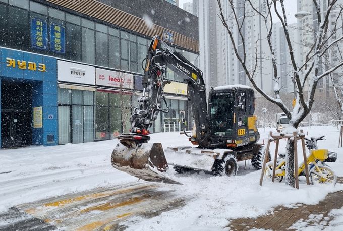 굴삭기를 활용해 이면도로에서 제설 작업을 하고 있다.