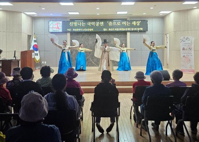 어르신들이 매송면 행정복지센터 대강당에서 공연단 '춤이랑'의 국악 공연을 관람하며 공연을 즐기고 있다